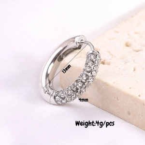 Macro shot of silver C-shaped hoop earrings featuring dense rows of sparkling zircons
