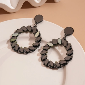 Detail of black geometric drop earrings with marble resin texture and twisted metal rings