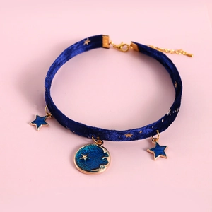 Close-up of starry blue velvet pet collar with gold-edged moon and star enamel pendants