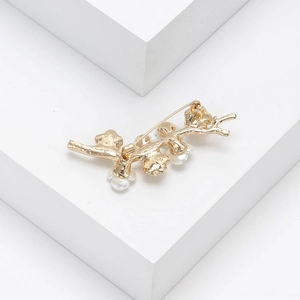 Close-up of golden branch brooch with white faux pearls on elegant geometric stands