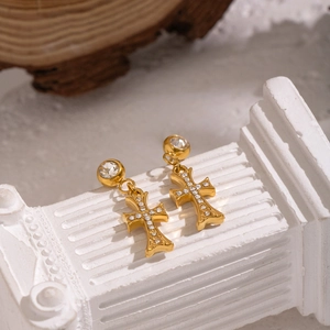Détail des boucles d'oreilles croix dorées avec incrustation de zircon sur socle