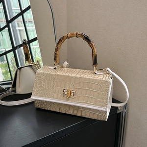 Detail of elegant beige crocodile-pattern leather bag with authentic bamboo handle