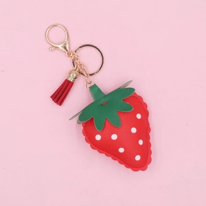 Cute red leather strawberry keychain with gold hardware and tassel on pink background