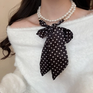 Close-up of double-layer pearl necklace with a large black and white polka dot silk bow