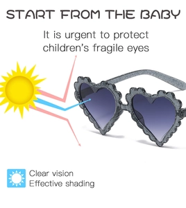 Detail of heart-shaped kids sunglasses with grey glitter frame and gradient lenses