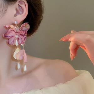 Detail of pink fabric flower earrings with long pearl tassels shown on a model