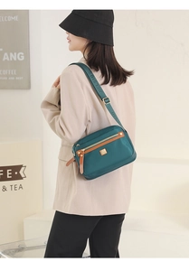 Detailed view of deep green nylon crossbody bag with multi-layer zippers and jacquard strap