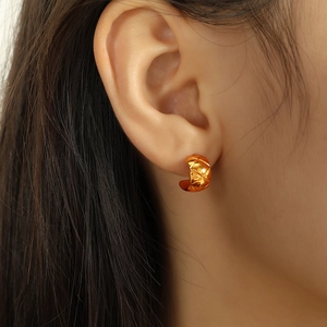 Minimalist gold C-shape stud earrings with quilted pattern on female ear model