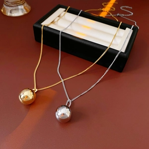 Close-up of gold and silver titanium steel necklaces with polished metal sphere pendants