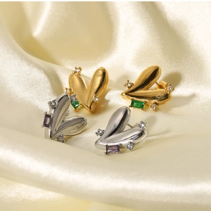 Macro detail of heart-shaped earrings with emerald and amethyst stones on silk