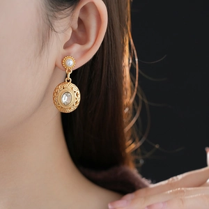 Detailed close-up of vintage golden earrings with round pearl and oval gem pendant