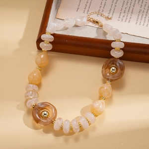 Detailed close-up of acrylic beaded necklace with gold spacers on vintage book background
