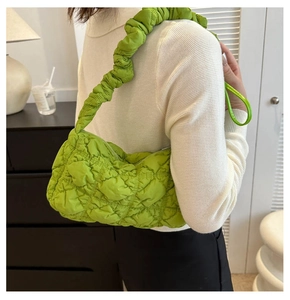 Close-up of green quilted cloud bag with ruched shoulder strap worn by a model