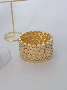 Close-up of golden multi-layer bracelet with colorful crystal smiley face relief details