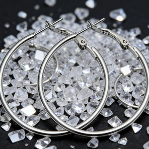 Macro view of large silver hoop earrings with polished finish on crystal stone background
