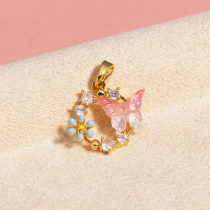 Macro detail of gold pendant with pink crystal butterfly and blue flower on velvet