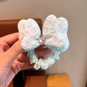 Detail of mint green bow hair tie with sparkling sequins and a pink crystal centerpiece
