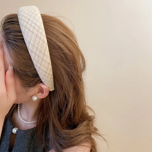 Dettaglio del cerchietto in tweed beige con orecchini di perle e collana abbinata