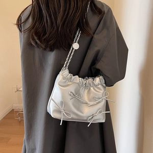 Silver bow shoulder bag with chain strap and metallic finish shown on model