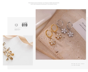 Detailed macro view of gold and silver flower earrings with white zircon petals