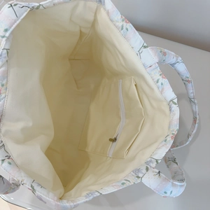 Close-up of the spacious interior lining and zipper pocket of a floral quilted tote bag