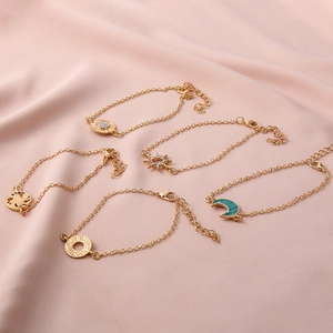 Detail of five gold-toned bracelets with celestial moon and sun charms on pink silk fabric