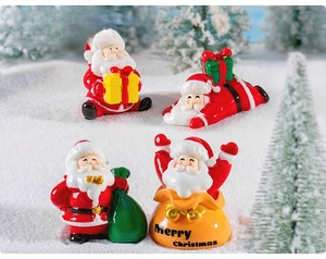 Miniature resin Santa Claus figures with Christmas tree decorations on a snowy background