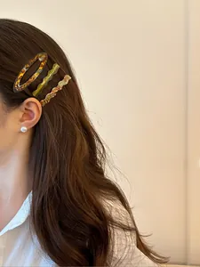 Close-up of elegant acetate hair clips and a pearl earring worn by a woman for hair styling