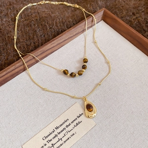 Detail of vintage double-layer gold necklace featuring tiger eye beads and teardrop pendant
