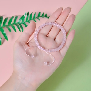 Close-up of a pink quartz woven bracelet worn on wrist with adjustable braided cord