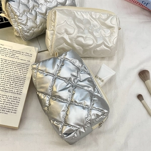 Detailed view of silver and white heart-quilted toiletry bags with metallic finish