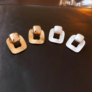 Detail of gold and silver square stud earrings with textured brushed finish on leather