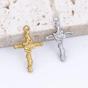 Macro detail of vintage rose and cross pendants in polished gold and silver steel