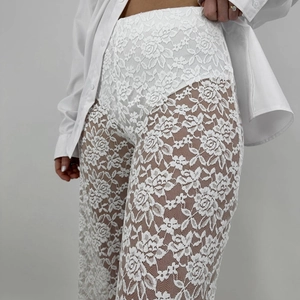 Dettaglio ravvicinato del pizzo floreale bianco dei pantaloni trasparenti a vita alta