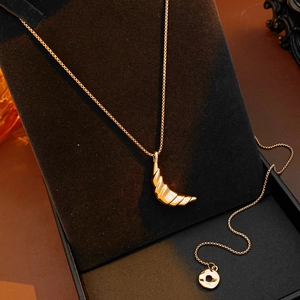 Close-up of 18k gold plated croissant crescent moon pendant on a dark velvet display
