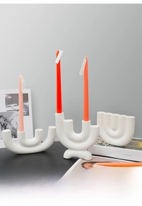 Modern white matte ceramic candle holder with colorful scented candles on a black table