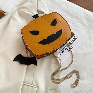 Close-up of pumpkin crossbody bag with bat charm and gold chain on stylish blazer