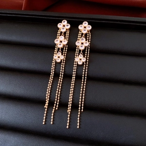 Detail of 18K gold-plated floral fringe earrings with white inlay on black leather