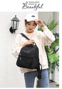 Detailed view of a black nylon backpack with adjustable straps worn by a model