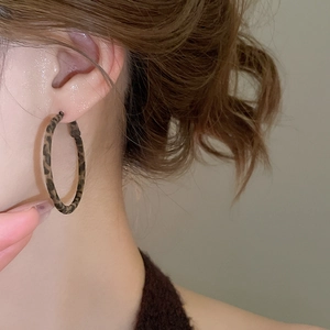 Gros plan de boucles d'oreilles créoles léopard sur un mannequin avec texture tissu