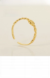 Détail d'une bague ajustable en acier doré avec perles et breloque pièce gravée