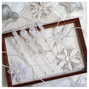 Detailed view of silver glitter snowflakes and icicle ornaments on white fabric tray