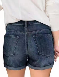 Macro shot of dark blue denim shorts featuring classic back pockets and rolled cuffs
