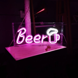 Pink neon Beer sign with beer mug icon on transparent acrylic board in a bar setting