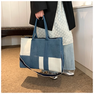 Detail of color-block canvas denim tote bag featuring dual handles and shoulder strap