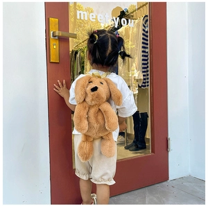 Toddler wearing a cute brown plush dog backpack with long ears in an outdoor setting