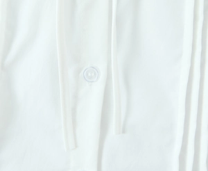 Detailed close-up of a white resin button and woven cotton texture on a slim square neck top