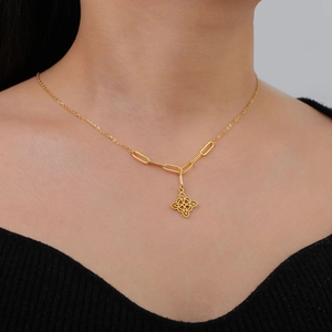 Detail of gold titanium witch knot pendant with layered mixed-link chain on model