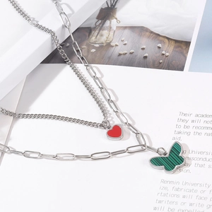 Detail of layered silver necklace with red heart and green malachite butterfly pendant