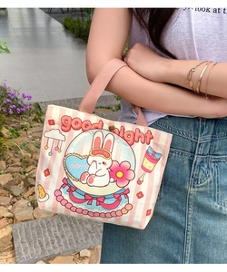 Outdoor shot of a pink striped canvas tote bag featuring a cute cartoon rabbit and typography
